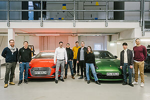 Gruppe von Studierenden, dazwischen zwei Autos